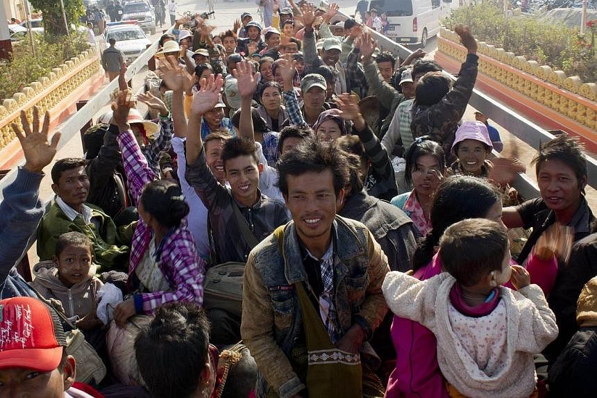 Residents who fled conflict areas near the Myanmar and Chinese border waving onboard a truck transporting them to a refugee camp in Mandalay on Feb 21, 2015. -- PHOTO: AFP