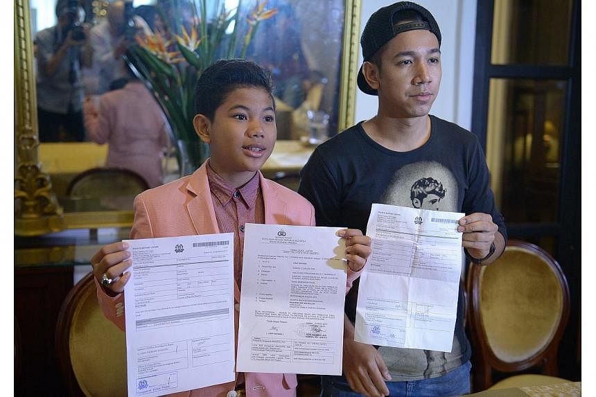 Tegar (left) and local singer Sufie Rashid showing the police reports lodged in Singapore and Indonesia at the press conference. -- ST PHOTO: DESMOND WEE&nbsp;