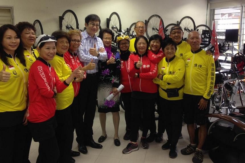 The Concern and Care Society cyclists together with chief executive David Lee (centre, in long-sleeved shirt) and chairman Margaret Wee (centre, in dress with floral prints). -- ST PHOTO: CHONG ZILIANG&nbsp;