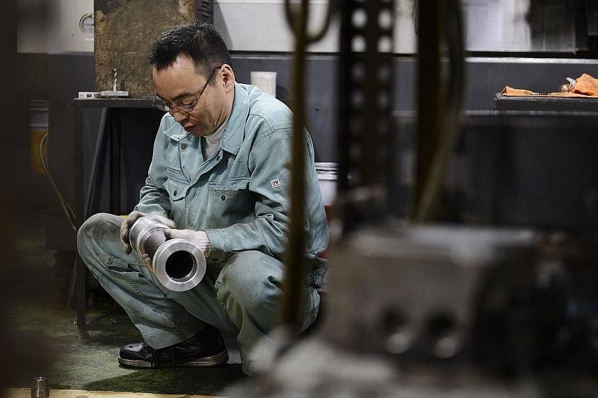 An employee inspecting a machined component at a Kyokuto Seiki Seisakusho K.K. metal machining factory in the Ota ward of Tokyo, Japan, on Dec 5, 2014. -- PHOTO: BLOOMBERG&nbsp;