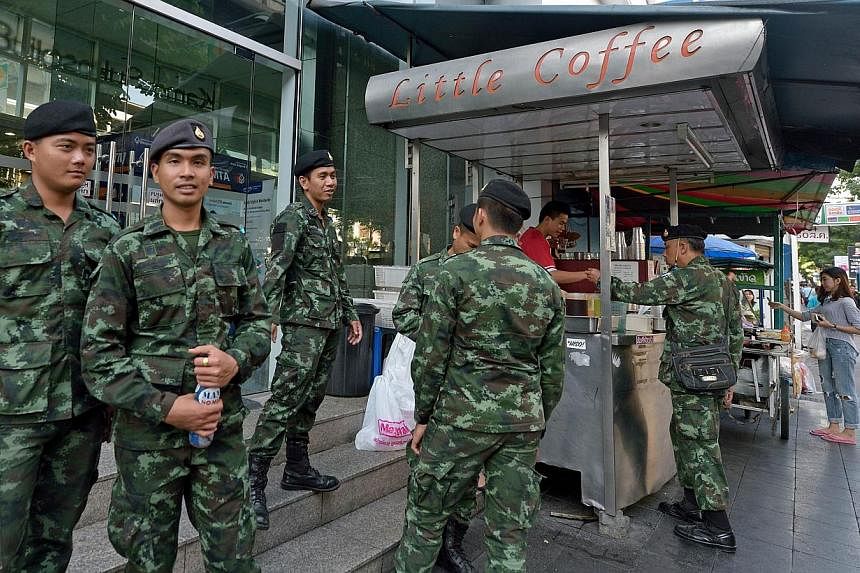 Thai soldiers standing along the pavement during a crackdown on sidewalk vendors along a main road in Bangkok on Nov 1, 2014. Thailand has repealed martial law some 10 months after it was imposed, amid a protracted political crisis. -- PHOTO: AFP