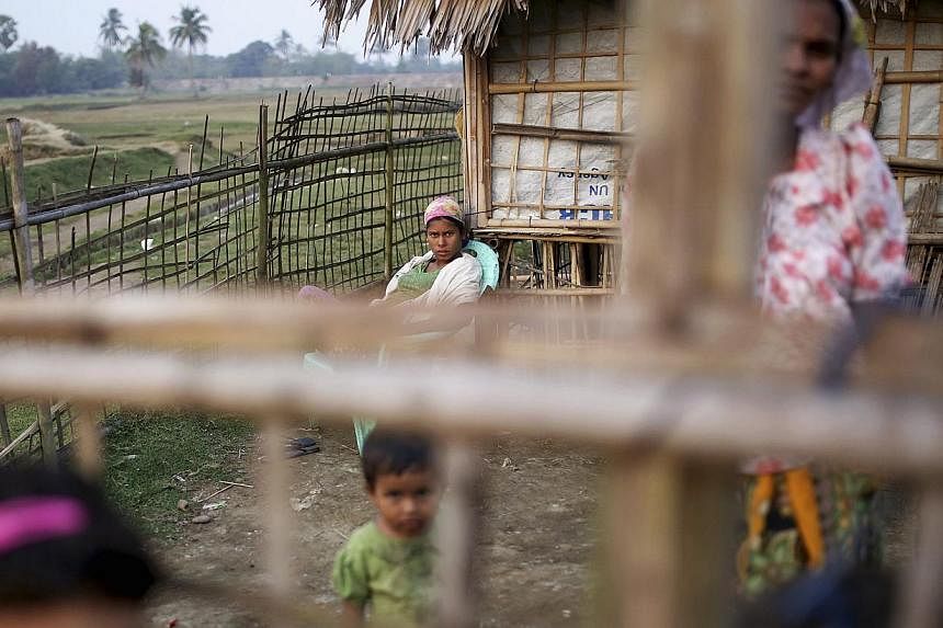 Internally displaced Rohingya women and children look from behind the fence of their temporary home at Thae Chaung IDP camp on the outskirts of Sittwe on Feb 15, 2015.&nbsp;Myanmar authorities have begun collecting temporary identification cards from