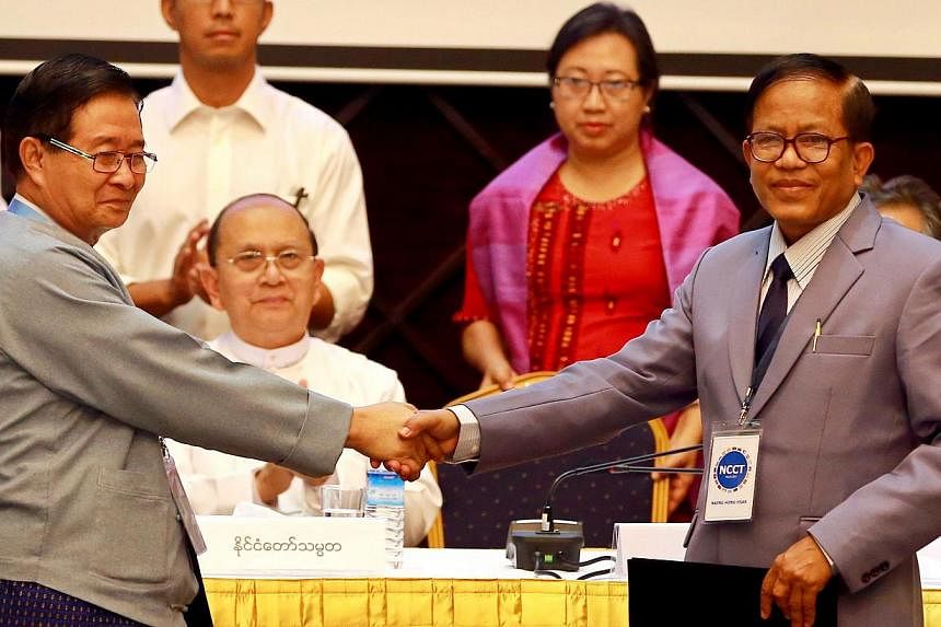 Union Peace-making Work Committee vice-chairman Aung Min (left) shaking hands with Nationwide Ceasefire Coordination Team leader Naing Han Tha after they signed the draft ceasefire pact yesterday. Myanmar President Thein Sein witnessed the signing of