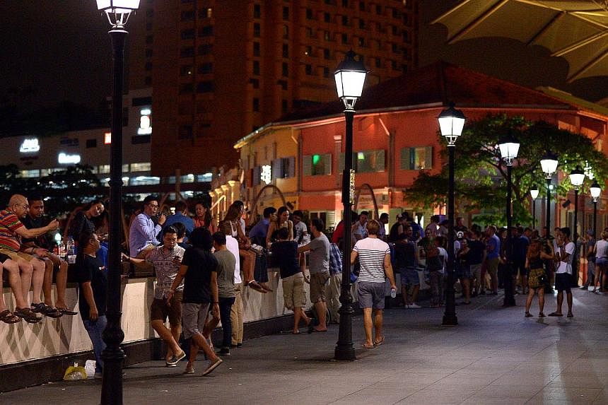 At least 200 people were seen on Read Bridge at Clarke Quay after midnight and drinking even though the new Liquor Control (Supply and Consumption) Act bans drinking in all public places from 10.30pm to 7am. -- ST PHOTO: DESMOND WEE'