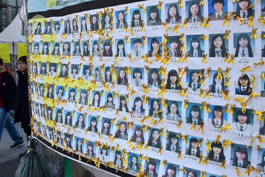 Pedestrians walk past portraits of the victims of the sunken South Korean ferry "Sewol" at Gwanghwamun square where relatives of the victims have been sitting in protest against the government, in Seoul on Jan 8, 2015. -- PHOTO: AFP