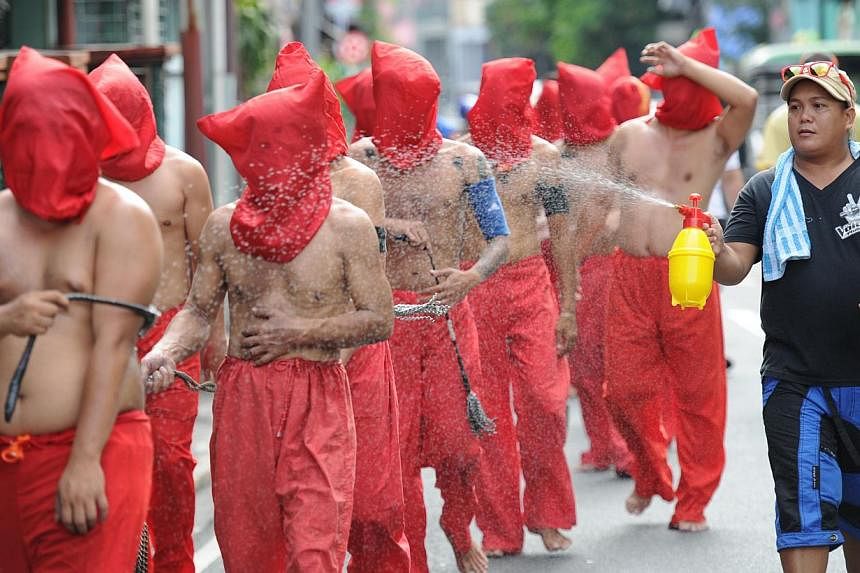 A man (right) sprays penitents with water to cool them down as they flagellate themselves as part of Lenten observance in Manila on April 2, 2015. -- PHOTO: AFP&nbsp;