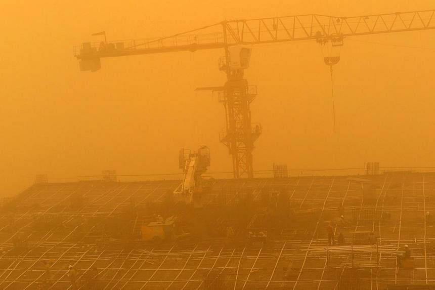 Construction workers are seen amid a sandstorm at one of construction sites in Dubai, United Arab Emirates, on April 2, 2015.&nbsp;Flights were disrupted, ships weighed anchor and schools were closed Thursday as a major sandstorm blew through Saudi A