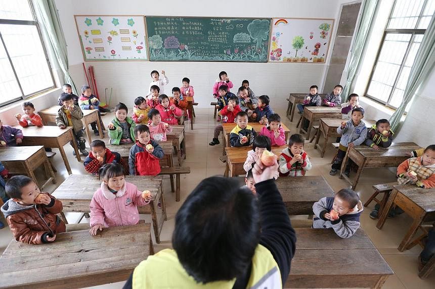A volunteer giving out apples to kindergarten pupils at a school in China. -- PHOTO: ST FILE&nbsp;