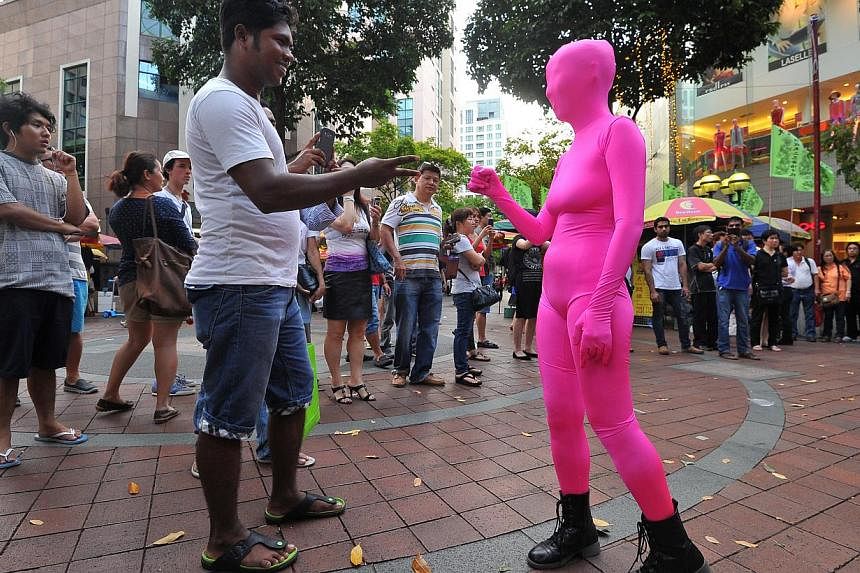 Zentai artists wearing full-body spandex costumes bemuse onlookers