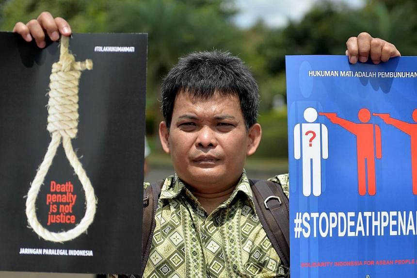 A protester holding up a placard that reads "'death row is a murder and death penalty is not justice" during an anti-death penalty rally in front of the palace in Jakarta on April 28, 2015. -- PHOTO: AFP&nbsp;
