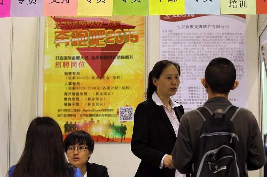Job seekers speaking with representatives at a job fair for Beijing-Tianjin-Hebei province enterprises in Beijing, China on April 29, 2015. -- PHOTO: EPA