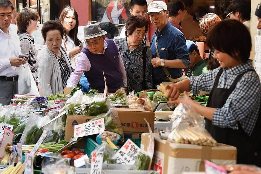 Shoppers choosing vegetables at a fruit and vegetable store in Tokyo on May 1, 2015. -- PHOTO: AFP&nbsp;