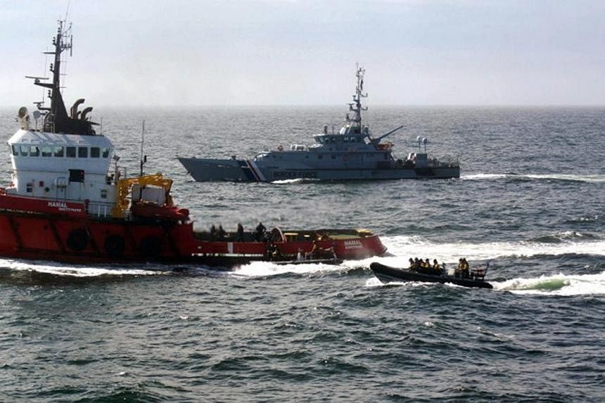 A handout photograph made available by the British National Crime Agency (NCA) on April 30, 2015, showing the MV Hamal (left) being boarded by a team from the British Royal Navy frigate HMS Somerset and Border Force cutter Valiant on April 23, 2015. 