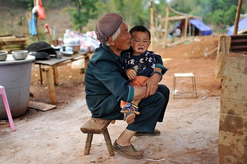 This picture taken on April 6, 2015, shows a Kokang refugee holding a child in her arms at a temporary shelter in the border area of China and Myanmar in Nansan township in Lincang, southwest China's Yunnan province. Tens of thousands of refugees hav