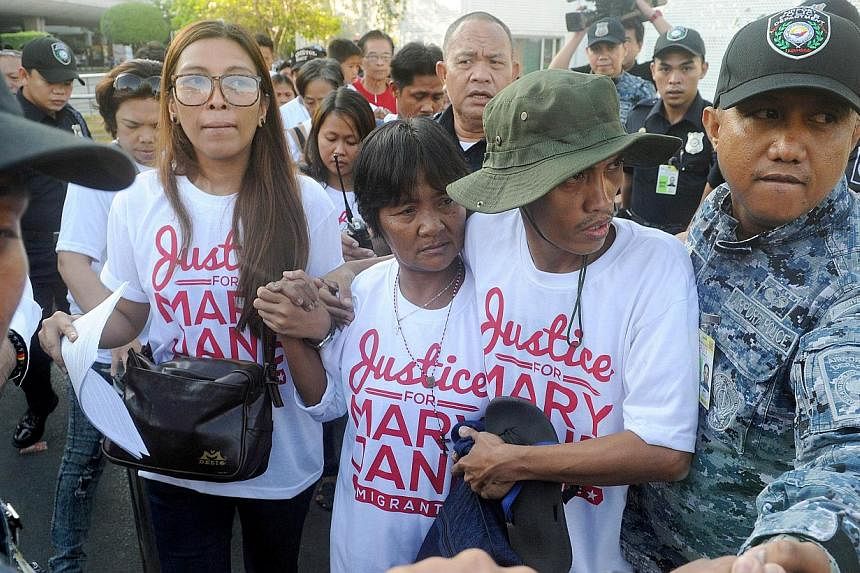 Celia Veloso (centre), the mother of Mary Jane Veloso, is escorted by a supporter upon her return from Jakarta in Manila on May 1, 2015. -- PHOTO: AFP