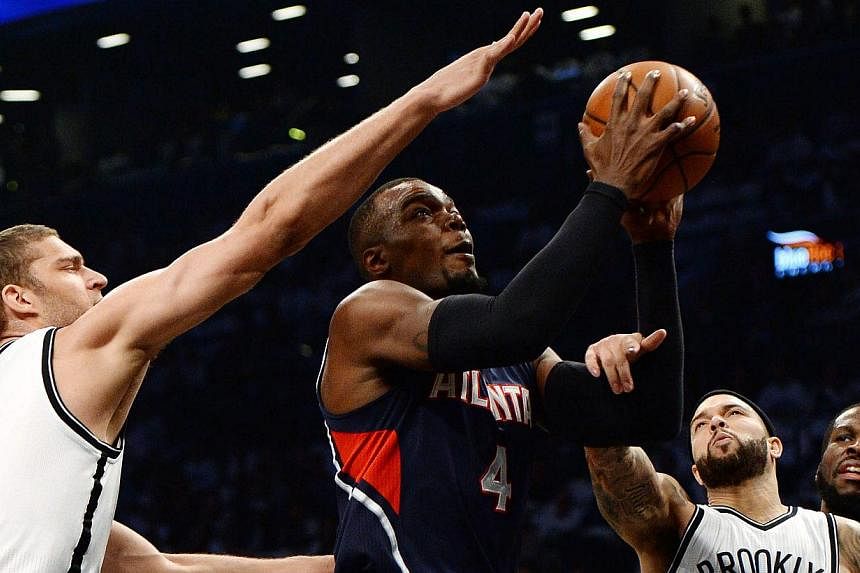 Atlanta Hawks' Paul Millsap (centre) drives to the basket past the Nets' Brook Lopez (left) and Deron Williams (right) during the first half of game six of the NBA playoff match at the Barclays Centre in Brooklyn, New York on&nbsp;May 1 2015. -- PHOT