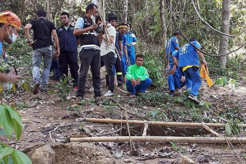 Rescue workers and forensic officials inspecting the site of a mass grave uncovered at an abandoned jungle camp in the Sadao district of Thailand's southern Songkhla province on May 1, 2015. -- PHOTO: AFP&nbsp;