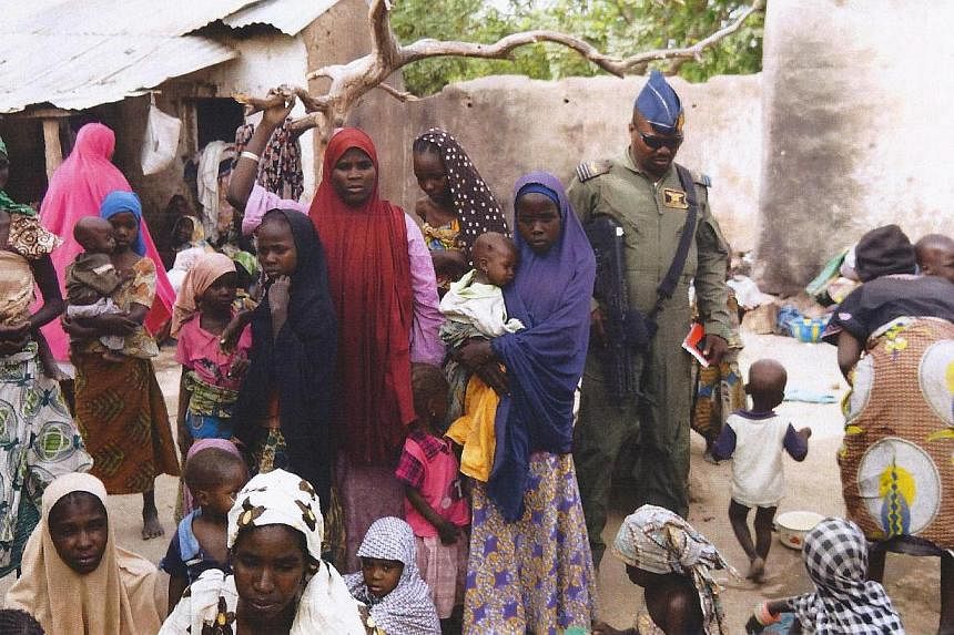 A member of the Nigerian Army standing next to a group of women and children rescued in an operation against the Islamist group Boko Haram in the Sambisa Forest, Borno state, on April 30, 2015. -- PHOTO: AFP