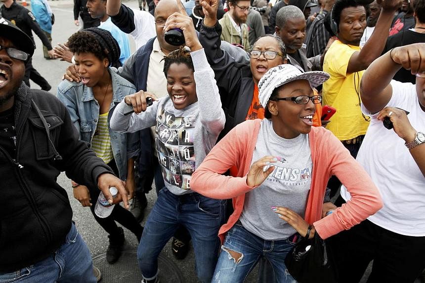 People celebrate as they gather in the streets of Baltimore, Maryland, on May 1, 2015, following the decision to charge six Baltimore police officers - including one with murder - in the death of Freddie Gray, a black man who was arrested and suffere