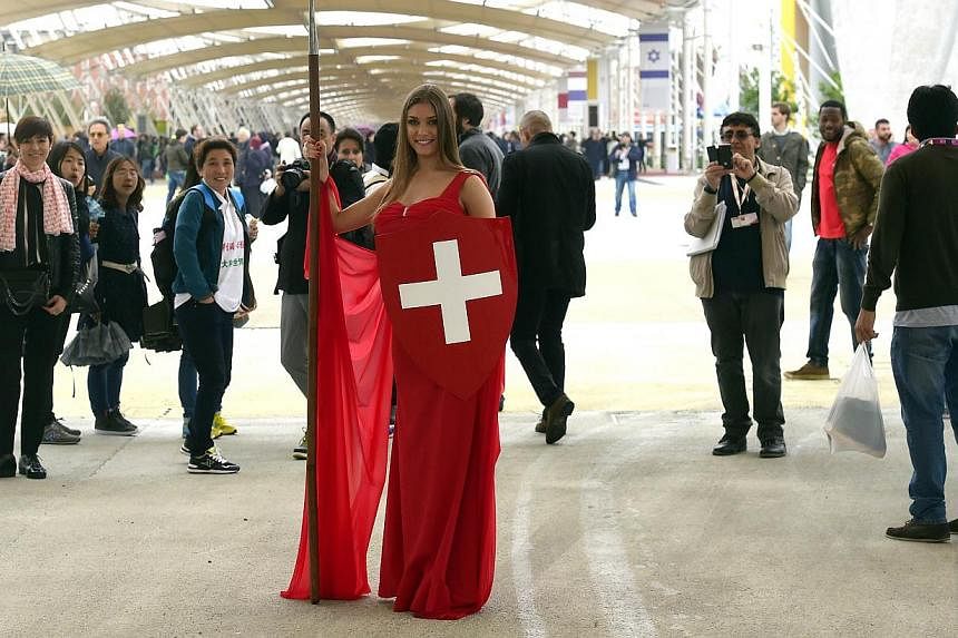 A model poses next to the Pavilion of Switzerland on May 1, 2015 in Milan, on the opening day of the Milan Expo. The opening of Expo 2015 was marred Friday by violent clashes between police and dozens of militants opposed to Milan’s hosting of the 