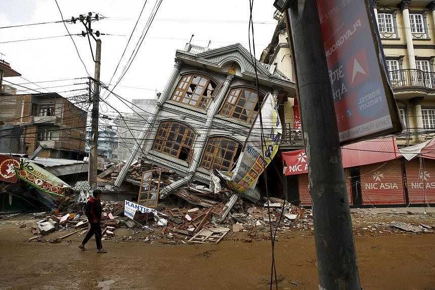 A man walks along the street near a collapsed house following Saturday's earthquake in Kathmandu, Nepal May 1, 2015. US military aircraft, heavy equipment and air traffic controllers will start arriving in Nepal from Saturday as part of a US relief o