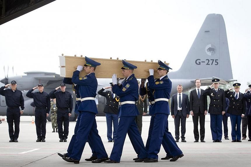 Ukrainian soldiers carry the coffins containing the last remains of Dutch victims of the MH17 Malaysia Airlines plane crash onto a Hercules C130 transport aircraft of the Royal Dutch Air Force prior to its departure from Kharkiv to Eindhoven on May 2