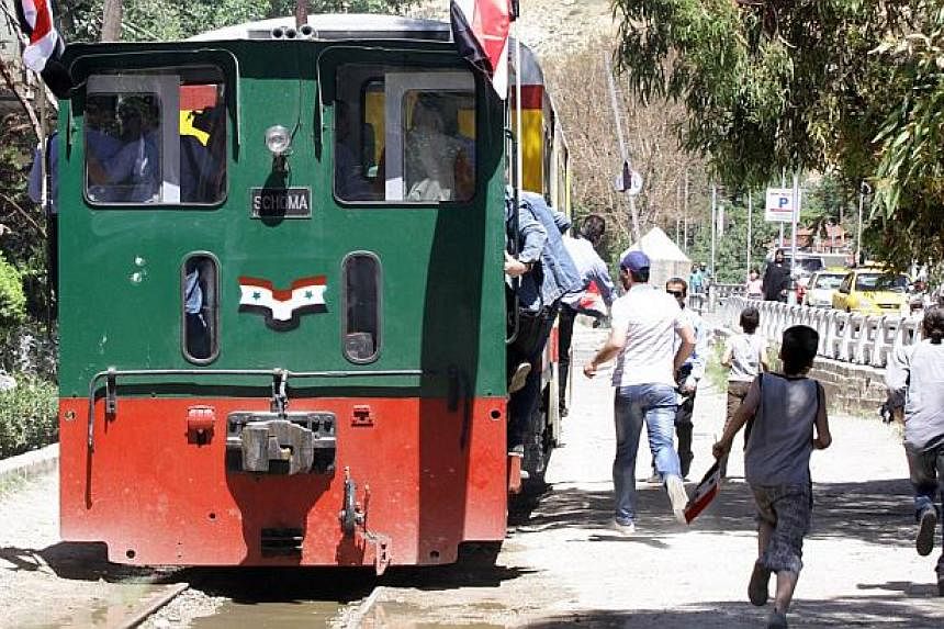 Syrians ride the tourist train flying Syrian flags in Damascus, following the re-opening ceremony of the rail route between two neighbourhoods in the Syrian capital, Rabwa and Dumar, on May 1, 2015. -- PHOTO: AFP&nbsp;