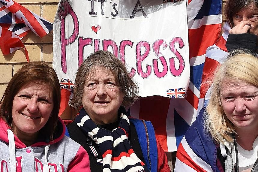 A sign saying 'It's a Princess' hangs above royal well-wishers outside Lindo Wing following the birth of a baby girl at St.Mary's Hospital in Paddington, west London, Britain, on May 2, 2015. Prince William and his wife Kate were to spend their first