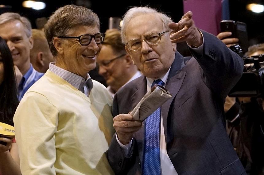 Berkshire Hathaway chief executive Warren Buffett (right) shows his friend Microsoft co-founder Bill Gates the finer points of newspaper tossing, prior to the Berkshire annual meeting in Omaha, Nebraska May 2, 2015. Berkshire Hathaway shareholders on