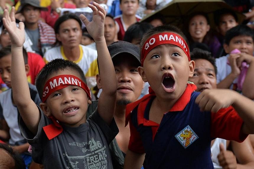 Fans watch a live telecast of the welterweight unification bout between Filipino boxer Manny Pacquiao and US boxer Floyd Mayweather, at a plaza in Marikina City suburban Manila on May 3, 2015. -- PHOTO: AFP