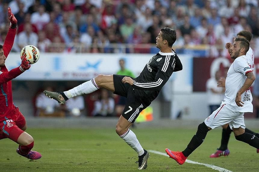 Real Madrid's Cristiano Ronaldo (centre) scores past Sevilla's goalkeeper Sergio Rico (left) on May 2, 2015. -- PHOTO: AFP&nbsp;