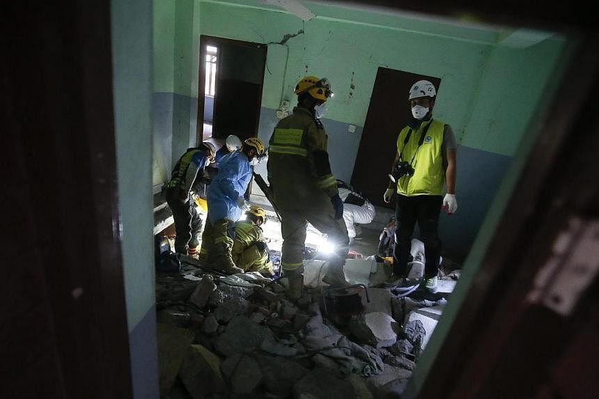 Members of Korea's Human in Love search and rescue team together with a team from Oman cut the floor of a room in a fallen building as they try to free the body of a woman, in Balaju, Kathmandu, Nepal, May 3, 2015.&nbsp;Nepal has asked foreign countr
