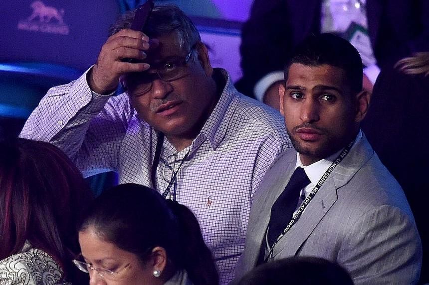 Boxer Amir Khan (right) watches the Leo Santa Cruz against Jose Cayetano featherweight bout on May 2, 2015 at MGM Grand Garden Arena in Las Vegas, Nevada on May 2, 2015. -- PHOTO: AFP