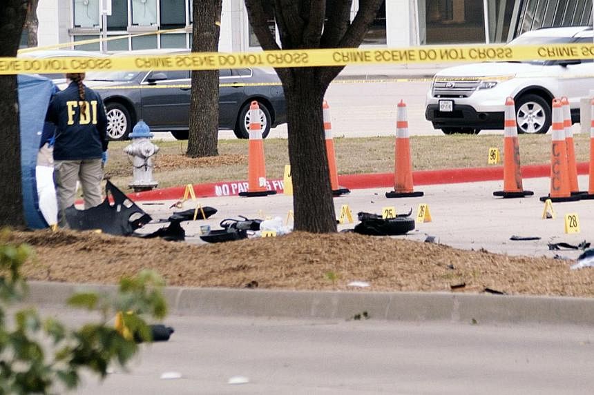 An FBI agent views debris of a car blown up by police as a precaution, near the Curtis Culwell Center on May 4, 2015 in Garland,Texas. Police in Texas shot dead two gunmen outside a Prophet Mohammed cartoon contest put on by a group that has a histor