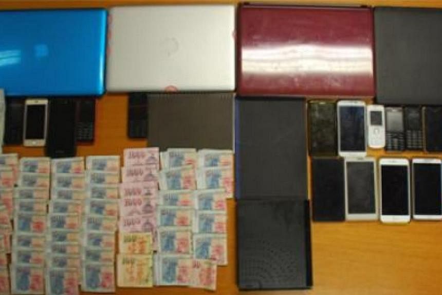 Police arrested nine men and two women suspected of being involved in a remote gambling operation, and seized cash amounting to about $215,000, computers, mobile phones, betting records and bank transaction record booklets. -- PHOTO: SINGAPORE POLICE
