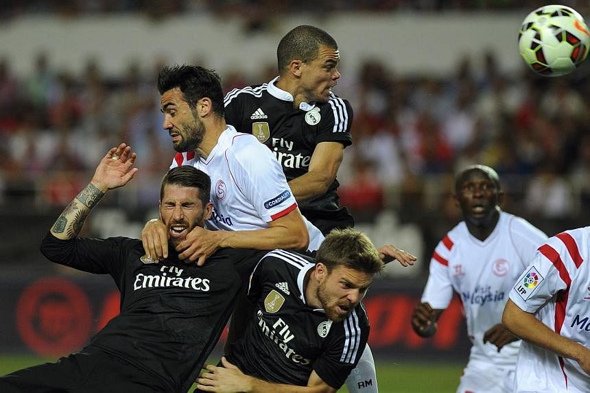 Real Madrid's defender Sergio Ramos (left), Portuguese defender Pepe (top right) and midfielder Asier Illarramendi (second left) vie with Sevilla's midfielder Vicente Iborra (top left) and midfielder Denis Suarez (right) during the Spanish league foo