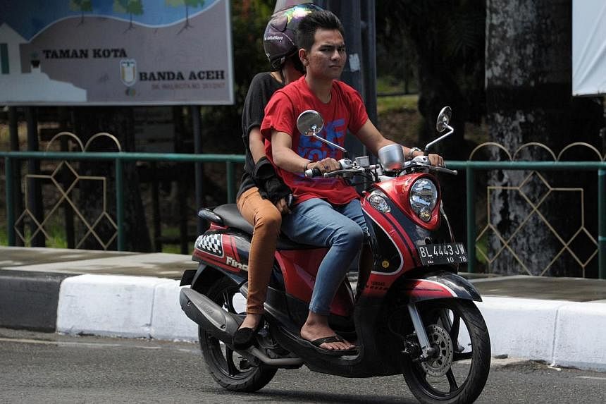 A man and a woman ride a motor bike in Banda Aceh on May 4, 2015. North Aceh district in Indonesia's Aceh has passed legislation banning unmarried men and women from riding together on motorbikes, a lawmaker said on May 4, the latest new Islamic regu