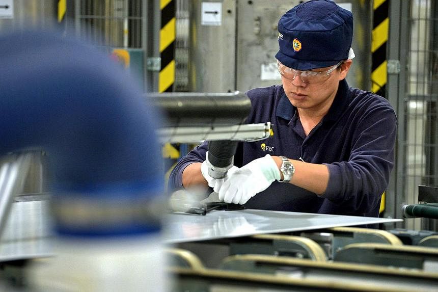 An employee works on solar panels on the module production line at the REC Solar ASA manufacturing facility in Tuas on Sept 5, 2014. Singapore's manufacturing PMI for April will be released on Monday, May 4, 2015. -- PHOTO: ST FILE