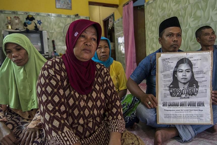 Family members of beheaded Indonesian maid Siti Zainab displaying a poster (right) bearing her portrait at their home in Bangkalan, East Java province, on April 15, 2015. Indonesia will stop sending new domestic workers to 21 Middle Eastern countries