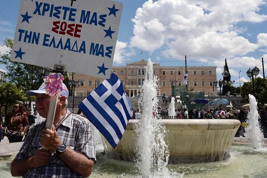 A man holds a Greek flag and a placard reading "Our Christ, save our Greece" in front of the Greek parliament in Athens on April 30, 2015. -- PHOTO: AFP&nbsp;