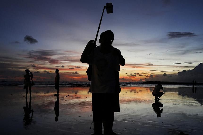 Tourists taking pictures during sunset in Kuta beach, Bali, on Feb 26, 2015. Singapore has emerged as the top contributor to tourist arrivals in Indonesia, with Bali and Bandung among the more popular destinations for Singaporeans. -- PHOTO: REUTERS&