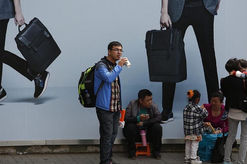Visiting mainland Chinese families rest under an advertisement board at a shopping district in Hong Kong on Feb 23, 2015.&nbsp;A female tour guide in Yunnan who castigated her tour group for not shopping enough was sacked, after a video of her scoldi