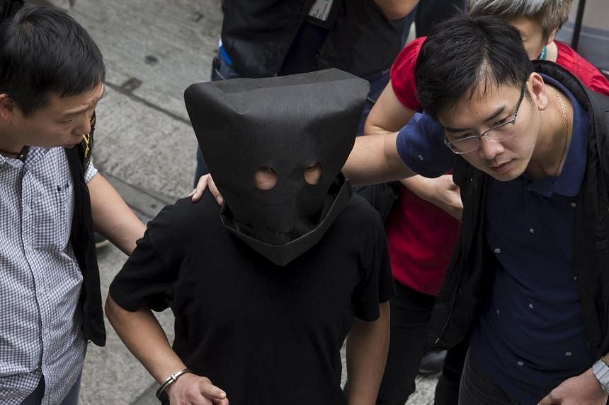 Police officers escort a man (centre, face covered), suspected to be involved in the kidnapping of a tycoon's granddaughter, as he is brought to Choi Hun MTR station for investigation in Hong Kong, China May 5, 2015. The kidnapping, an armed robbery 