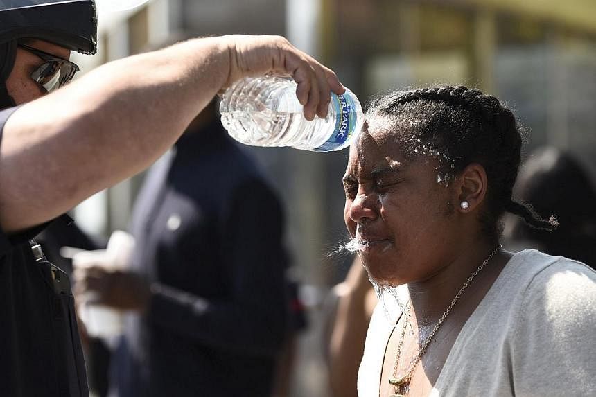 A law enforcement officer washes the face of a woman who was affected by pepper spray in Baltimore, as protests threatened to arrest again after a false shooting report. -- PHOTO: REUTERS