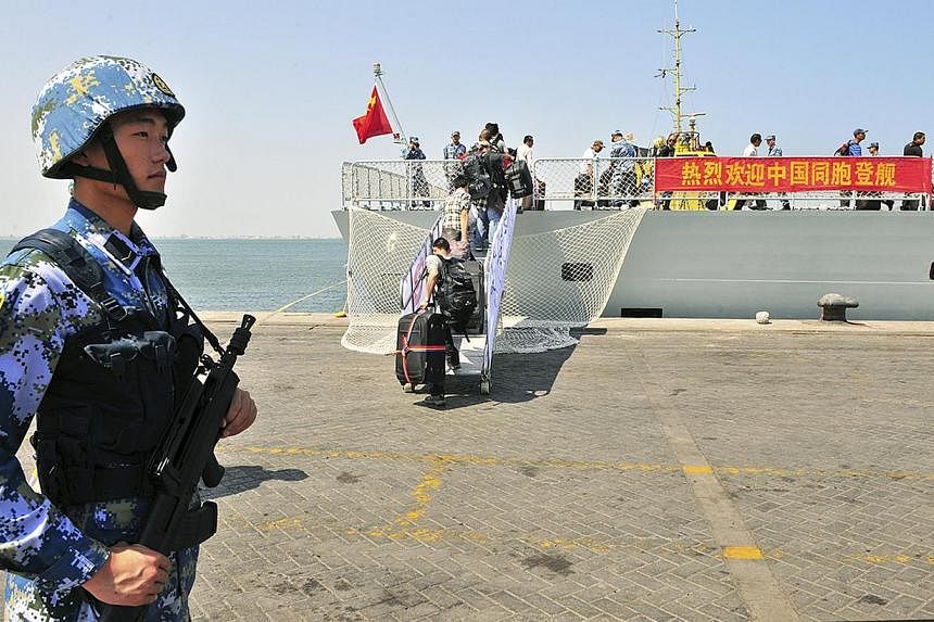 A navy soldier (left) of People's Liberation Army (PLA) stands guard as Chinese citizens board the naval ship "Linyi" at a port in Aden, on March 29, 2015. -- PHOTO: REUTERS