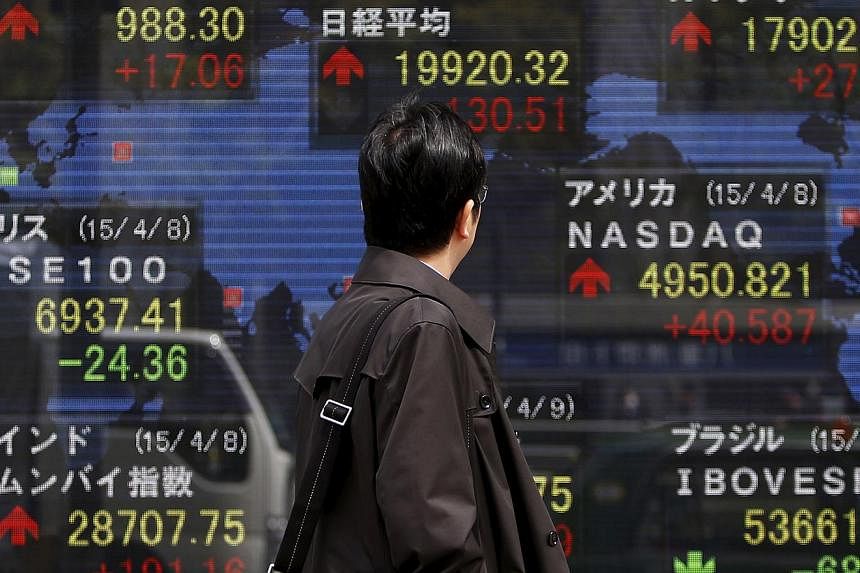 A pedestrian looking at an electronic board showing the stock market indices of various countries outside a brokerage in Tokyo on April 9, 2015. Asian stocks stumbled on Wednesday in sympathy with weak US and European markets as equities investors we