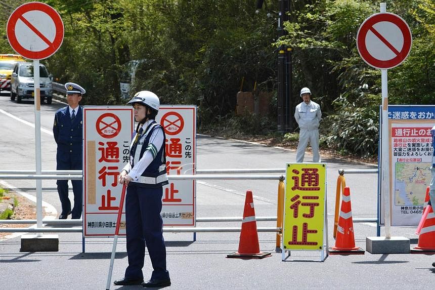 Police and other officials standing at a roadblock halting access to a popular hot springs resort in Hakone, Kanagawa prefecture on May 6, 2015. -- PHOTO: AFP