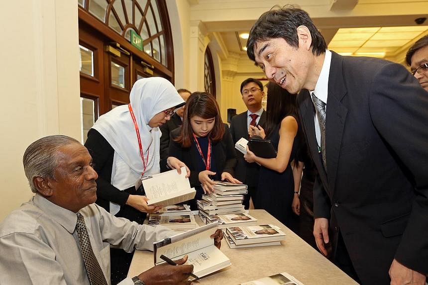 Professor Jayakumar autographing a copy of his book for Mr Haruhisa Takeuchi, Japan Ambassador to Singapore. -- ST PHOTO: SEAH KWANG PENG