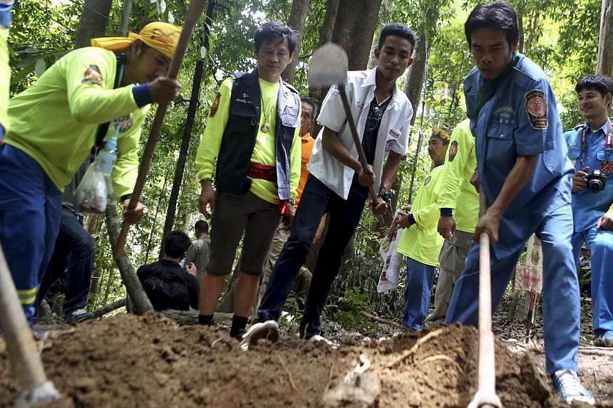 Thai rescue workers dig to recover human remains of suspected Rohingya refugees after discovering a second abandoned migrant trafficking camp at a jungle on a mountain in the Sadao district, Songkhla province, near the Thai-Malaysian border in southe