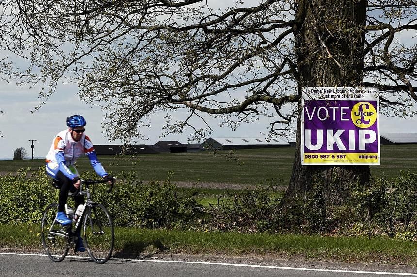 A cyclist riding past a UK Independence Party (UKIP) election campaign poster on the outskirts of Aylesbury, north-west of London, on April 30, 2015. UKIP candidate Robert Blay has been suspended after a video of him insulting Conservative rival Rani